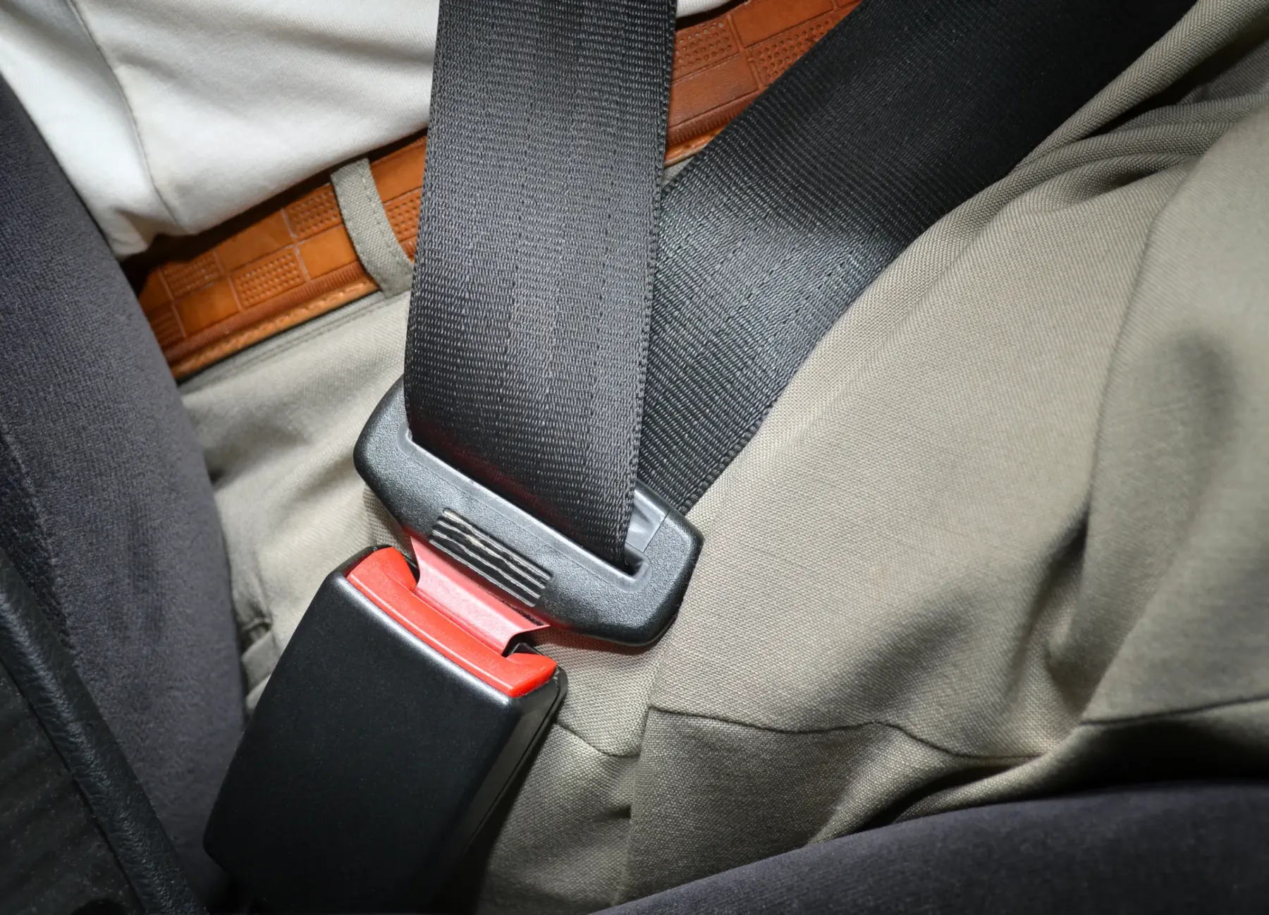 A fastened three-point seat belt across the lap and chest of a seated occupant in a working vehicle cabin