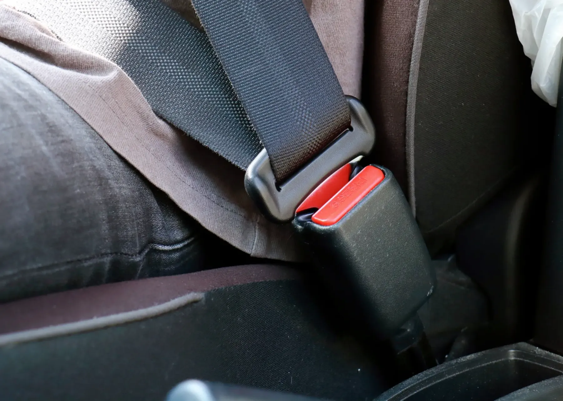 A fastened seat belt in a vehicle interior with the latch plate seated in the buckle and the webbing running over the occupant's lap