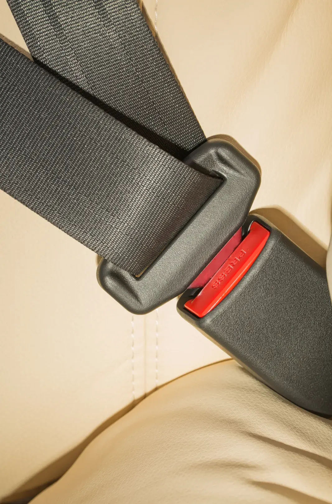 A seat belt fastened across an occupant showing the webbing, the moulded latch plate and the buckle housing in close detail